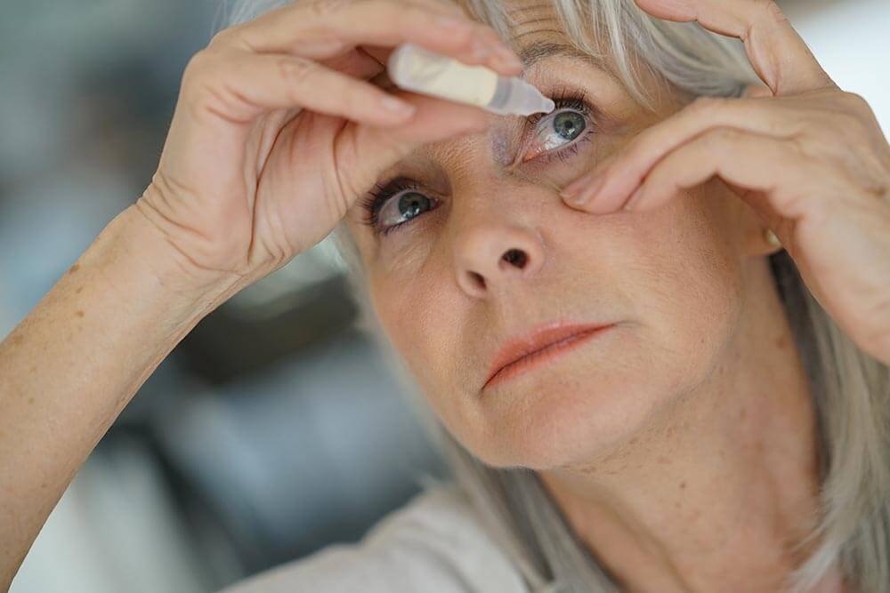 Older woman putting drops in her eye